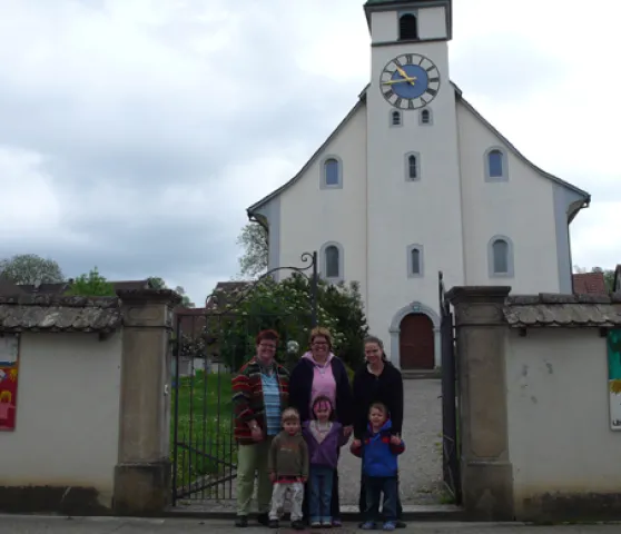 Famigo-Plakate frontal (Foto: Lukas P. Huber) Famigo-Plakate frontal: Das Familiengottesdienst-Team Bettina Pfistner, Claudia Ochsner-Schmid und Manuela Etzweiler mit drei Kindern vor der Kirchenmauer, an der die Familiengottesdienst-Plakate angebracht sind. (Foto: Lukas P. Huber)