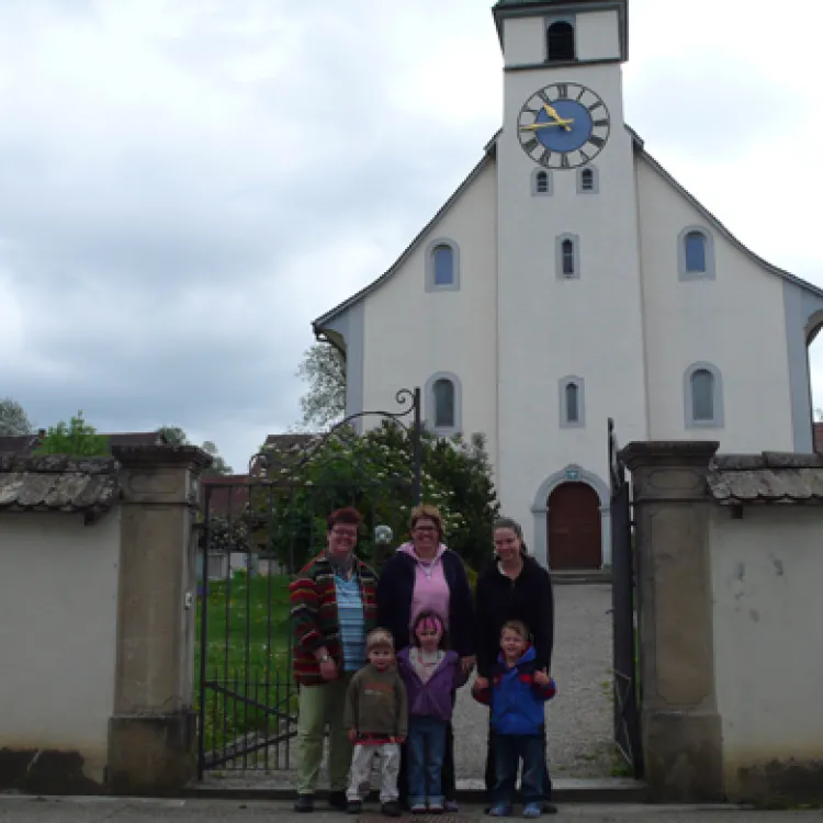 Famigo-Plakate frontal (Foto: Lukas P. Huber) Famigo-Plakate frontal: Das Familiengottesdienst-Team Bettina Pfistner, Claudia Ochsner-Schmid und Manuela Etzweiler mit drei Kindern vor der Kirchenmauer, an der die Familiengottesdienst-Plakate angebracht sind. (Foto: Lukas P. Huber)
